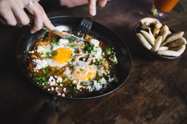 Çatal ve bıçakla kızarmış yumurta yiyen bir kadın.