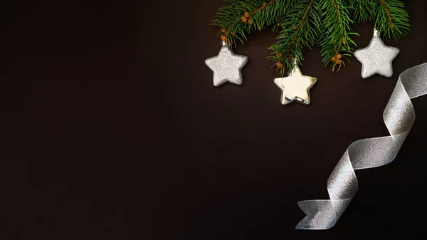 メリークリスマスとハッピーホリデーグリーティングカード フレーム バナー 暗い背景にクリスマスモミの木の枝 銀の星 銀リボン 冬休みのテーマ ノエル平面 コピースペース — ストック写真