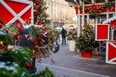 Bir sürü el yapımı süslemelerle dolu Noel panayırı büfesi. Avrupa şehir caddesinde kış tatillerinde süslenmiş çiçeklerle süslenmiş lüks mağaza önü.