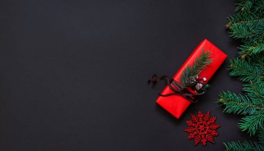 Noel hala hayattır. Kırmızı süslemeli bir hediye kutusu ve koyu bir arka plan. Lüks yeni yıl hediyesi. Noel hediyesi. Hediye kutulu Noel arkaplanı. Noel kutlaması.