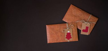 Karanlık arka planda yeni köknar dalları ve Kraft kağıdından oluşan bir Noel sınırı. Mutlu Noeller ve mutlu tatiller! Düz konum, üst görünüm, kopyalama alanı.