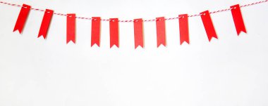 Noel kompozisyonu. Kırmızı küçük bayraklardan ve pastel arka planda kırmızı saten şeritten yapılmış çelenkler. Noel, kış, yeni yıl konsepti. Minimum kış tatili fikri düz döşeme, üst manzara, kopyalama alanı..