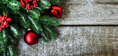 Noel ağacı dalları, süslemeleri ve kırmızı topları kırsal ahşap masada olan tebrik kartı için Noel arkaplanı. Metin için kopyalama alanı olan üst görünüm.