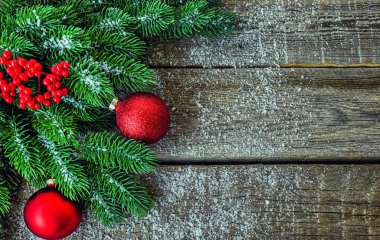 Noel ağacı dalları, süslemeleri ve kırmızı topları kırsal ahşap masada olan tebrik kartı için Noel arkaplanı. Metin için kopyalama alanı olan üst görünüm.