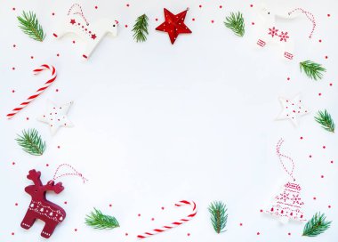 Kırmızı ve beyaz süslemeli Noel çerçevesi, eski tahta oyuncaklar, köknar dalları, pastel arka planda şeker kamışı. Noel, kış, yeni yıl konsepti. Metin için kopyalama alanı olan üst görünüm.