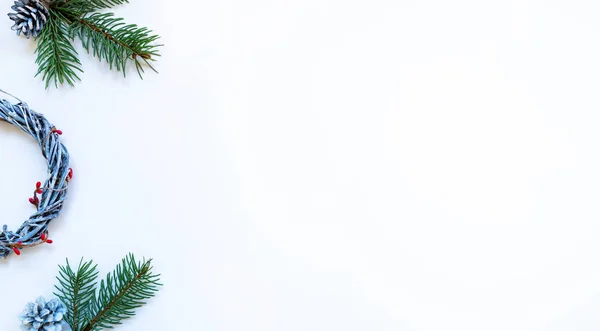 Christmas composition. Wreaths, red berries, fir branches and pine cones on pastel gray background. Christmas, winter, new year concept. Flat lay, top view, copy space.