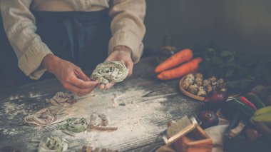 Peynirli İtalyan makarnası ve sebzeli şef manzarası. Tahta tahtada İtalyan usulü makarna ve koyu ahşap arka planda makarna pişirmek için malzemeler..