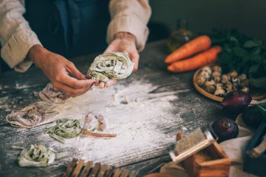 Peynirli İtalyan makarnası ve sebzeli şef manzarası. Tahta tahtada İtalyan usulü makarna ve koyu ahşap arka planda makarna pişirmek için malzemeler..
