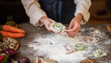 Peynirli İtalyan makarnası ve sebzeli şef manzarası. Tahta tahtada İtalyan usulü makarna ve koyu ahşap arka planda makarna pişirmek için malzemeler..