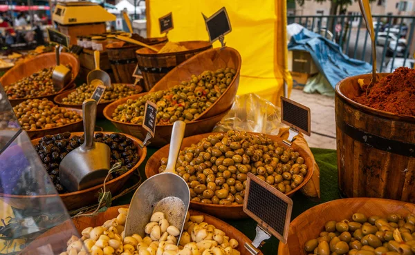 Selling organic fresh agricultural product at farmer market. Fresh organic produce stall at a farmers market. Marinated olives on street market in Provence, France. Selling and buying.