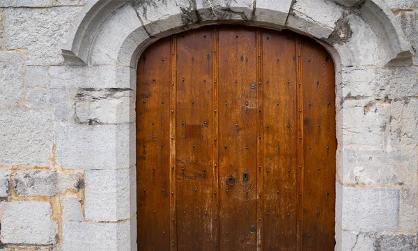 Medieval castle gate. Ancient wooden door in old stone castle wall. Locked wooden door with metal forging.