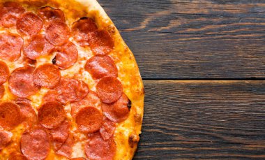 Tahta masada pizza var. Pizzacıların tanıtım posteri, şablon. Esmer arka planda geleneksel İtalyan pizzası. Pizza menüsü. Yukarıdan bak. Metin için boşluk.