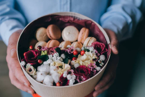 Floral shop concept . Florist man creates flower arrangement in a round box. Beautiful bouquet of mixed flowers. Handsome fresh bunch. Flowers delivery.