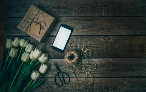 Anneler günü, sevgililer günü, kadınlar günü, bahar tatilleri mevsimsel satış, alışveriş, aşk, özel teklif, indirim. Akıllı telefon, hediye ve eski ahşap arka planda laleler. Reklam için düzenleme.