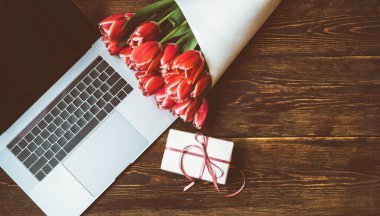 Anneler günü, sevgililer günü, kadınlar günü, bahar tatilleri mevsimsel satış, alışveriş, aşk, özel teklif, indirim. Eski ahşap arka planda dizüstü bilgisayar, hediye ve laleler, alışveriş afişi şablonu.