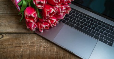 Çalışma alanı ya da iş yeri. Laptop, çiçekler ve Rustik ahşap arka planda fotokopi alanı olan hediye kutusu. Bahar ya da iş kavramı. Üst manzara, düz uzanma.