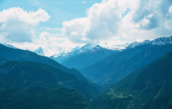 山の谷の風景 スイスの山々の美しい景色 霧に覆われたぼんやりと青い山 アルプスの家 斜面の牧草地 雪に覆われた山々 — ストック写真