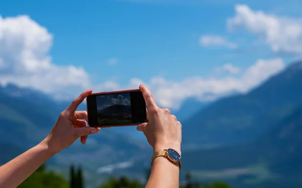 スイスアルプスの写真を撮るためにスマートフォンのカメラを使う若い女性 女性旅行ブロガーは夏の旅行休暇中に携帯電話で写真を撮る — ストック写真