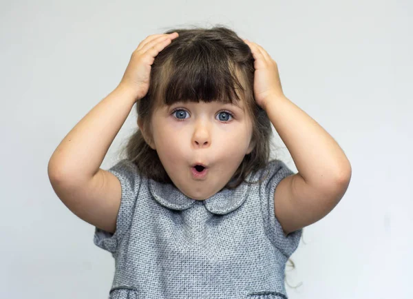 Портрет маленької дівчинки, що тримає руки на голові, кричить з відкритим ротом і божевільним виразом . — стокове фото