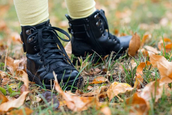 Pés e pernas de criança em pé nas folhas de outono — Fotografia de Stock