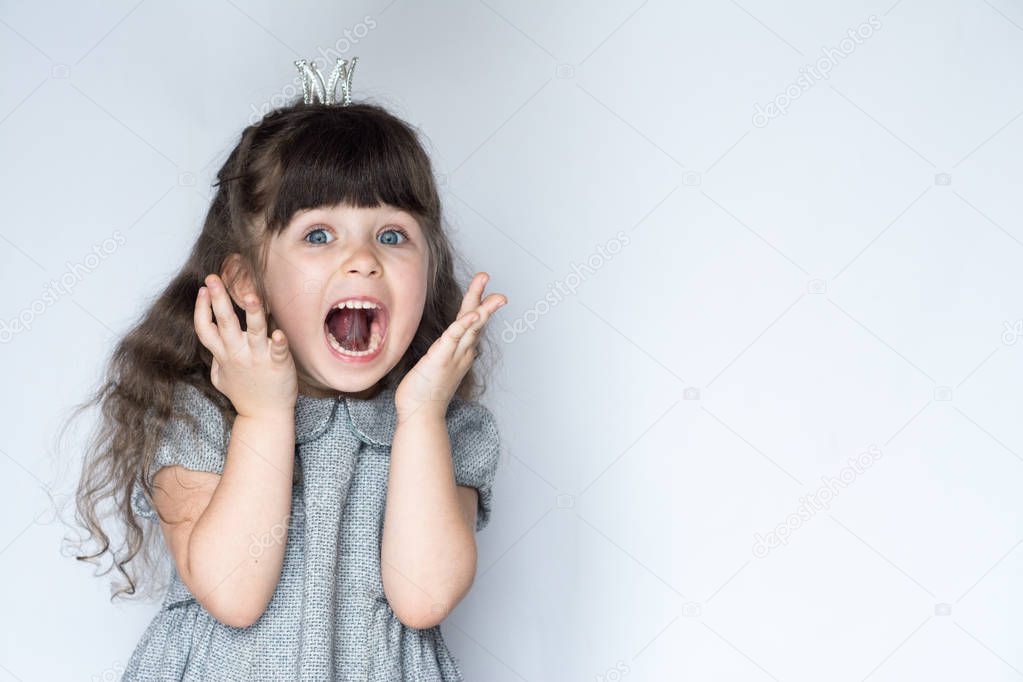 Portrait of 4-5 years old girl, screaming with open mouth and crazy expression. Surprised or shocked face. Free space for advertisement.