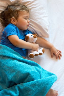 Şirin bebek çocuk oyuncak ile evde yatakta uyuyor. Boş alan