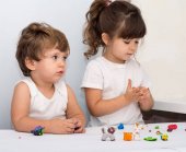 Két aranyos gyerek szórakozik együtt színes modellező agyagból készült, és egy óvoda. Kreatív gyerekek formázó otthon. Fiú és lány játék gyurma vagy tészta.