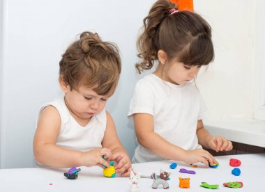 Yürümeye başlayan çocuk ve dört yıl kız having oyunculuk ile birlikte renkli kil bir günlük bakım, modelleme. Hamuru veya hamur ile çocuk oyun.