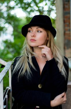 Bir güzel ciddi şık moda sarışın genç kadın sonbahar siyah ceket ve siyah şapka kapalı görünümlü dış saha, dikey resim