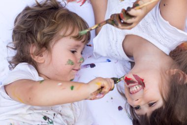 Komik çocuk ve kız beyaz arka plan üzerinde izole renkli boya boyalı ellerle