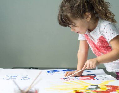 Dört yıl eski çocuk evde çiziyor. Boya fırçası ve suluboya ile güzel küçük kız.