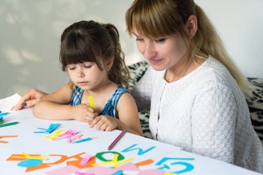 Çocuk yazmak öğrenme. Yetişkin kadın çocuk alfabeyi öğretir..
