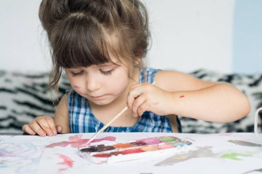 Güzel bir çocuk çiziyor. Boya Fırçası ve suluboya ile güzel küçük kız.