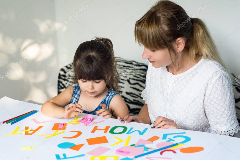 Mother or teacher teaching child english language alphabets