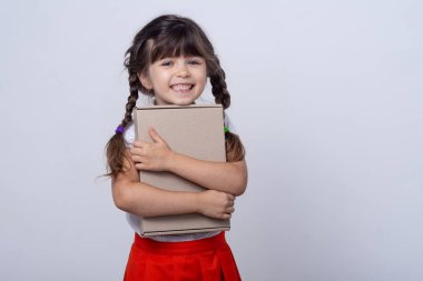 Üzerine istediğiniz metni yazabileceğiniz boş afişlere çocuklar. Çocuk eşyası reklamı. Beyaz arka planda izole edilmiş. Karton kutu tutan çocuklar. Küçük gülümseyen kız hediye kutusunu tutuyor.. 