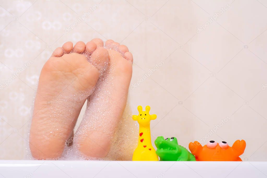 Children taking bubble bath. Child bathing in bathtub. Little girl playing with water. Rubber toys in foam bath