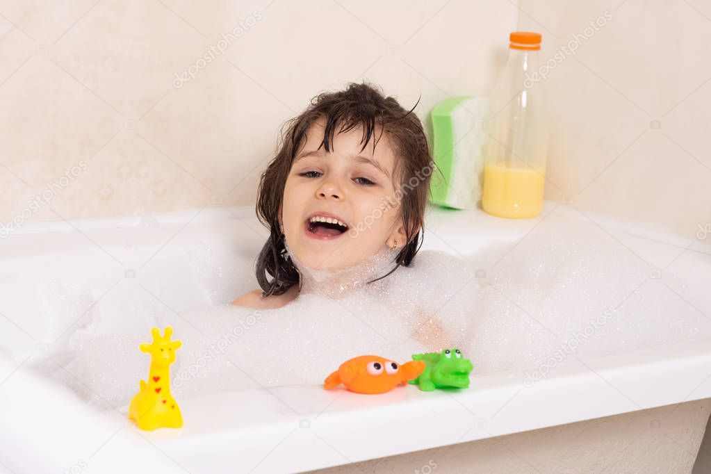 Kids taking bubble bath. Child bathing in bathtub. Little girl playing with water. Rubber duck in foam bath.