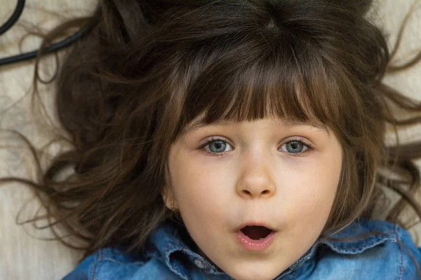 Awesome kid girl surprise face. Little girl with curly brown-haired, big blue eyes 6 or 5 years old, smiling at camera. Happy kids concept.