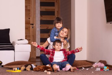 Evde iki çocuğu kucaklayan mutlu genç bir anne. Kardeşler. Yaşam biçimi