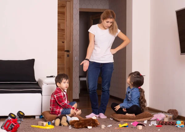 Mom tired to tidy up the house. Child scattered toys. Mess in the house. Siblings