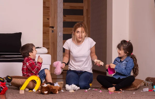 Mom tired to tidy up the house. Child scattered toys. Mess in the house. Siblings