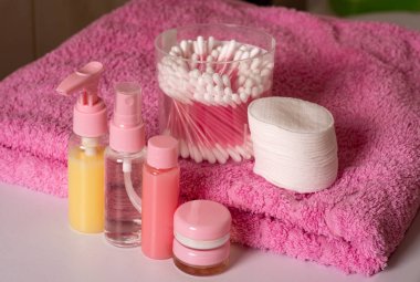 Pembe havluda kozmetik ürünler seti. Şampuan, maske, saç kremi, duş jeli için kozmetik paket koleksiyonu.