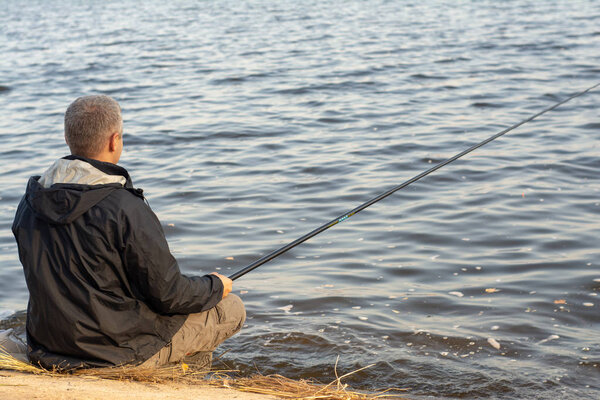 Cherkassy, Ukraine/November 1, 2019: Fisherman with fishing rod is fishing on the embankment of the River. Soft focus