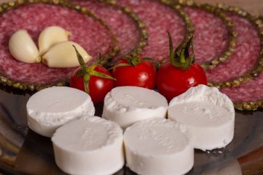 Domates, mozzarella dilimleriyle birlikte büyük bir servis tabağında. Caprese ve salam..