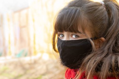 Corona Covid 19 'dan kendini korumak için maske takan genç bir kız.
