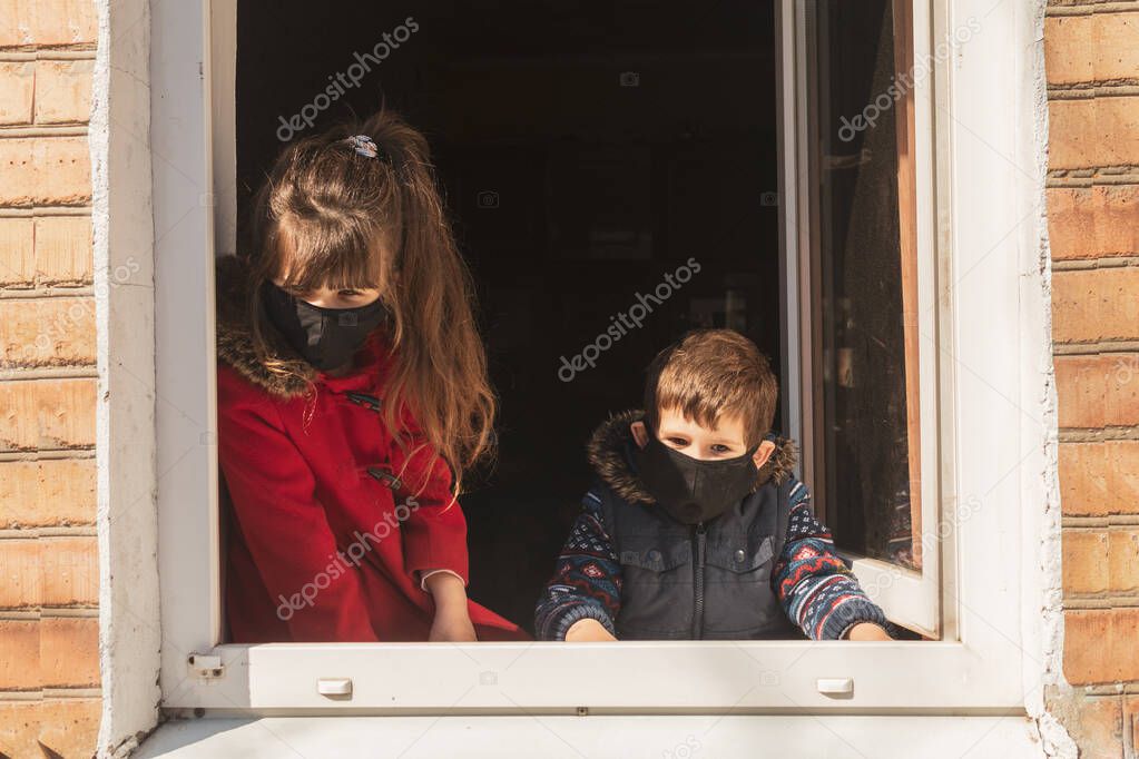 Coronavirus Covid-19, quarantine motivational photo. Kids stay at home to reduce risk of infection and spreading the virus. Girl and boy with a face mask on.