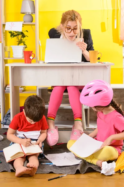 Work from home with kids. Parents work on laptop with children playing around. Children make noise and disturb mom at work. Busy mother