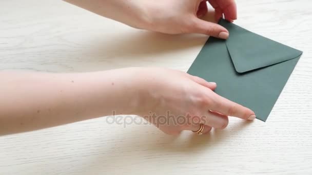Woman hand put envelops and flower on wooden table background
