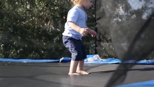 Cámara lenta de un lindo niño saltando en un trampolín — Vídeos de Stock