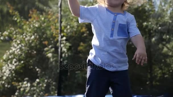 Szczęśliwy małe dziecko blond brązowe oczy skoki po raz pierwszy i zabawy na zewnątrz, zwolnionym tempie. Mały rozmiar trampolina na podwórzu domu. Słodkie małe dziecko, skoki na trampolinie. — Wideo stockowe
